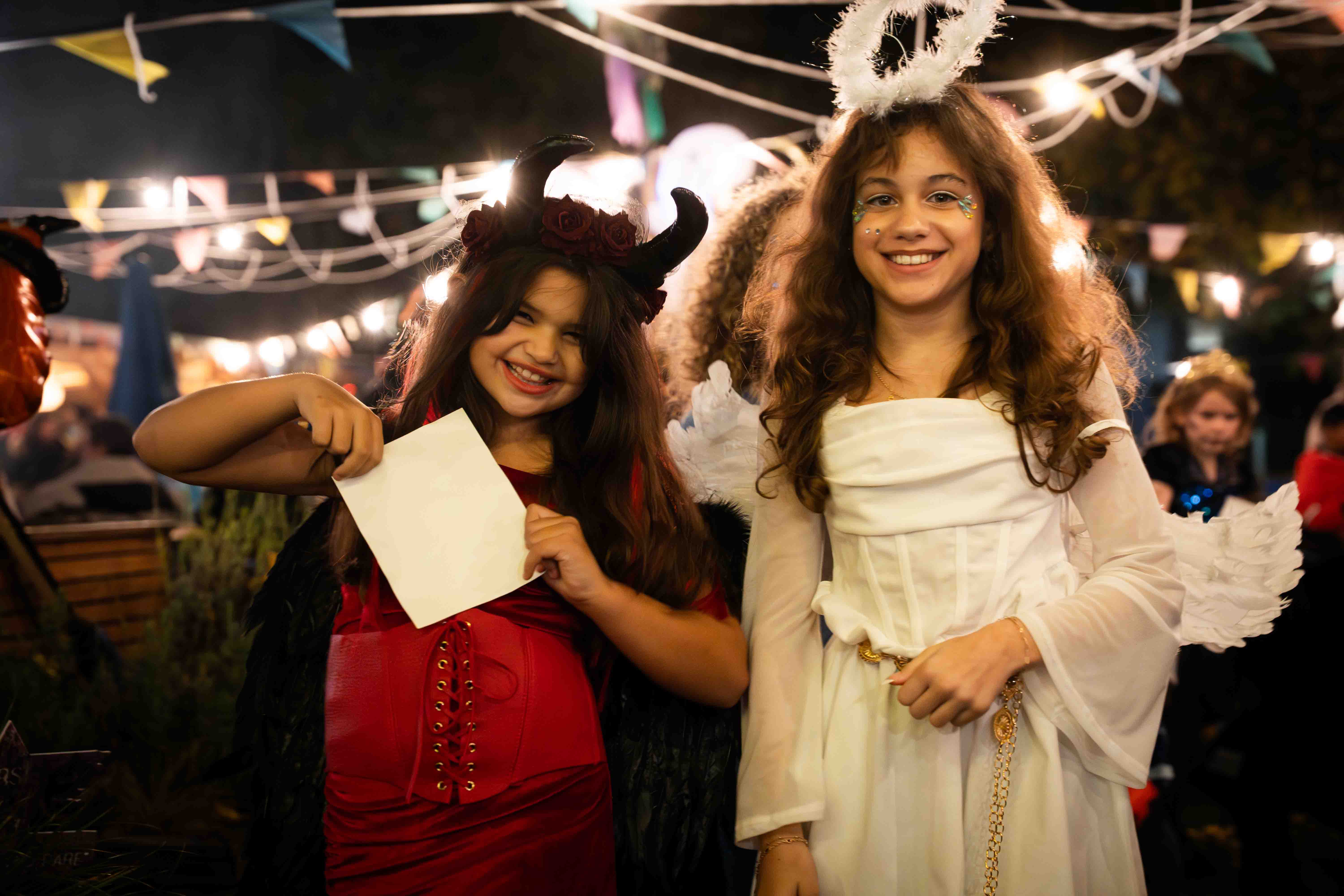 Two young girls dressed as an angel and devil at Halloween event